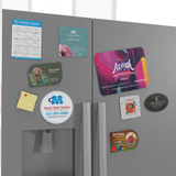 A collection of postcard magnets on a refrigerator in different shapes, including a rounded square shape.